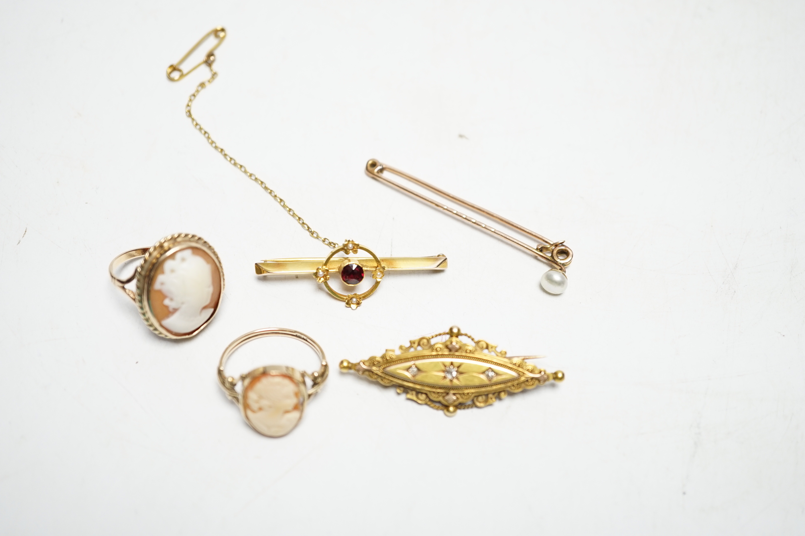 A late Victorian 15ct gold and three stone diamond chip set brooch, 43mm, an early 20th century yellow metal, garnet and seed pearl set bar brooch, two 9ct and oval cameo shell set rings and a yellow metal and cultured p